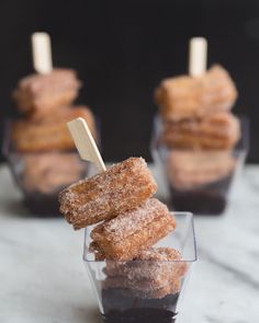 some sugared donuts in small cups with toothpicks sticking out of them