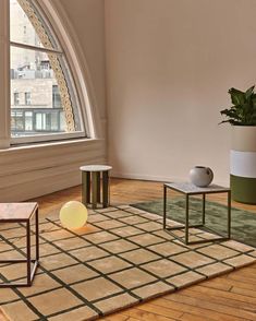 a living room with two tables and a potted plant on the floor in front of a large window