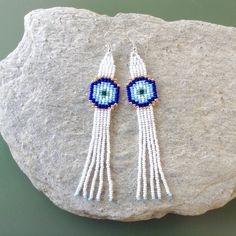 Lucky Eye Tassel Earrings,Blue Eye Fringe Earrings,Minimalist Boho,Protection Jewelry,Dangle Earrings,Long Seed Beaded Earrings Dimensions: Width- 0.8 inches /2cm Length (incl. ear wires)- 4.7 inches /12 cm These adorable earrings are a fun and lovely accessory, perfect for a gift or just for no reason! They are made from OUR ORIGINAL pattern, made from high quality glass beads, very lightweight. *Please note that real colors may slightly differ from their appearance on your display! Ready to Sh White Tassel Earrings With Latkans As Gift, White Tassel Earrings With Latkans For Gift, White Dangle Tassel Earrings With Latkans, White Drop Earrings With Latkans, White Latkans Drop Earrings, White Latkan Drop Earrings, Gift Long Drop Tassel Earrings, Tasseled Drop Earrings As Gift, Handmade White Dangle Plug Earrings