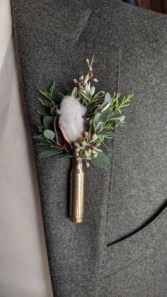 a boutonniere with cotton and greenery on the lapel of a suit