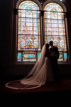 a bride and groom standing in front of stained glass windows at the end of their wedding day