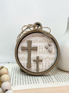 a clock with a cross on it sitting next to a white vase and some beads