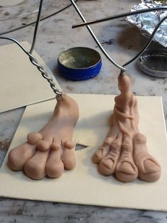 two feet are being made out of clay on a piece of paper with scissors and wire