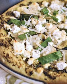 a pizza with spinach, artichokes and feta cheese on it