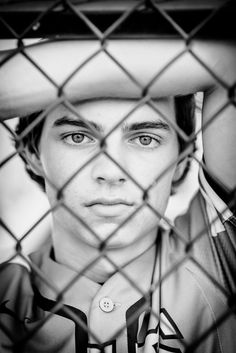 black and white photograph of a young man behind a chain link fence