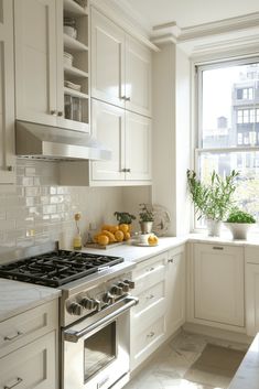 a kitchen with white cabinets and marble counter tops is shown in front of a window