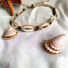 two seashells and one starfish on a white bed sheet with a beaded bracelet