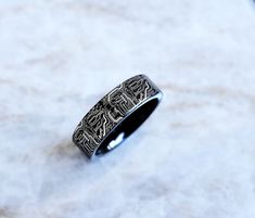 a silver ring with an intricate design on the inside is sitting on a marble surface