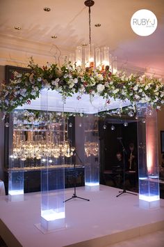 an event setup with flowers and lights on the ceiling, surrounded by clear acrylic columns