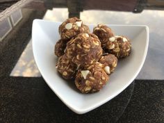 a white bowl filled with chocolate and nuts on top of a table next to a window