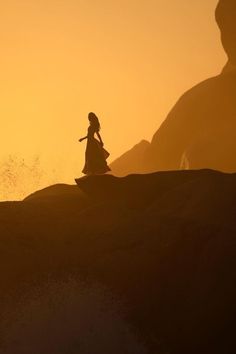 a woman standing on top of a sandy hill