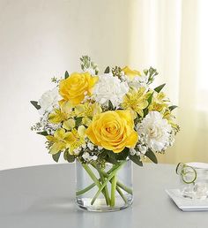 a glass vase filled with yellow and white flowers