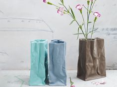 two vases with flowers in them sitting on a table next to paper bags and scissors