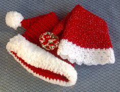 two red and white knitted hats laying next to each other on a gray surface