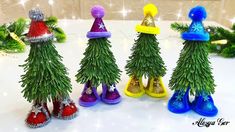 four small christmas trees with hats and boots in front of some fake firs on a table