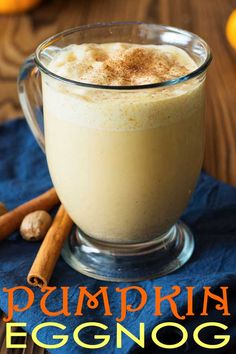 a glass mug filled with cinnamon and topped with whipped cream on top of a blue napkin next to oranges