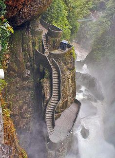 the stairs are built into the side of the cliff by the water and fog in the air