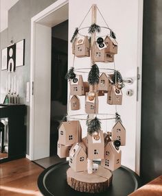 a christmas tree made out of cardboard with houses and ornaments hanging from it's sides