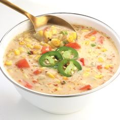 a white bowl filled with soup and topped with green peppers, corn and jalapenos