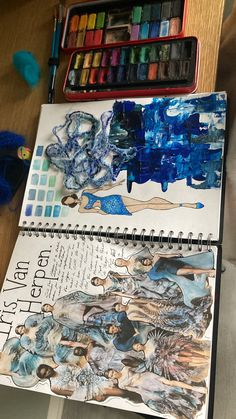 an artist's notebook with watercolors and other art supplies on the table