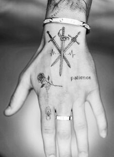 a person's hand with a tattoo on it and two crossed swords in the middle