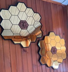 two mirrors hanging on the side of a wooden wall next to a mirror with hexagonal shapes