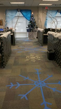 an office decorated for christmas with blue snowflakes on the floor and trees in the background