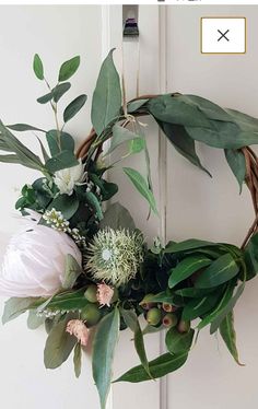 a wreath with flowers and greenery hanging on the front door for an easy diy project