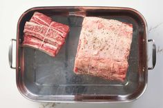 two pieces of raw meat sitting on top of a metal pan next to each other