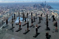 a group of people doing yoga on top of a building with the city in the background