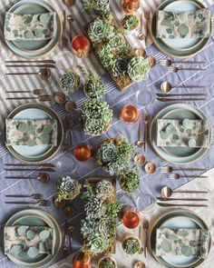 the table is set with succulents and place settings