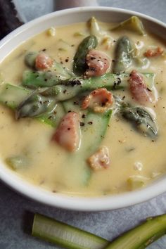 a white bowl filled with soup next to some celery stalks on a table