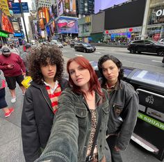 three young women taking a selfie on the sidewalk in times square, new york city