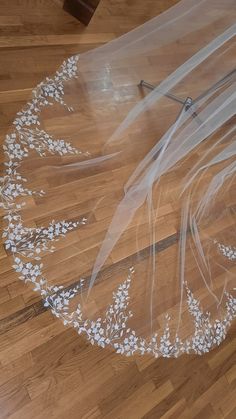 a wedding veil with white flowers on it sitting on top of a hard wood floor