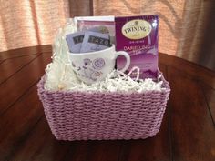 a wicker basket with coffee, tea and other items in it on a wooden table