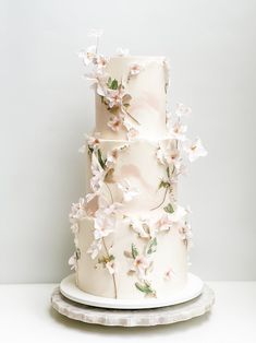 a three tiered white cake with pink flowers on the outside and green leaves on the inside