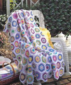 a crocheted blanket sitting on top of a white chair next to a table