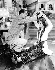 an old photo of a man helping a woman put on her hat while sitting down