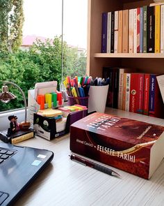 a laptop computer sitting on top of a desk next to a bookshelf filled with books