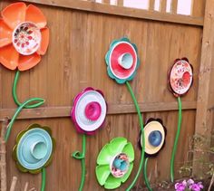 there are many colorful flowers on the wall behind this fence and it looks like they have been made out of paper