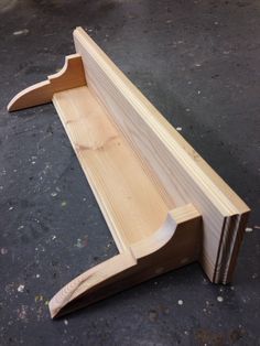 a wooden bench sitting on top of a black floor next to a piece of wood