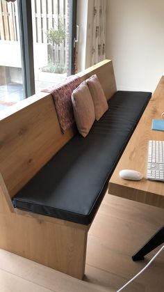 a wooden bench sitting next to a window with a keyboard and mouse on top of it