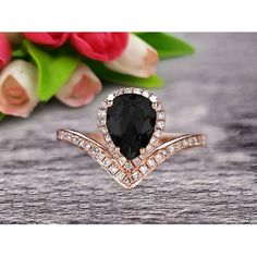 a black diamond ring sitting on top of a wooden table next to pink roses and tulips