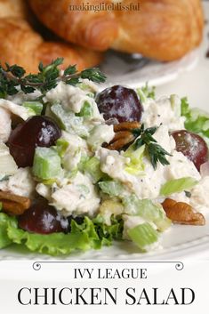 chicken salad with grapes and nuts on a white plate next to croissants