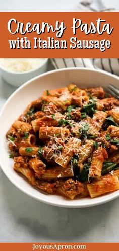 creamy pasta with italian sausage and spinach in a white bowl on a marble table