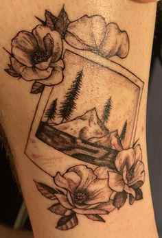 a woman's thigh with an image of flowers and mountains in the frame on it