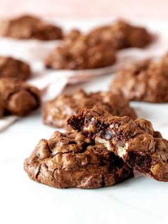 chocolate cookies with white crumbs and one broken in half on a counter top