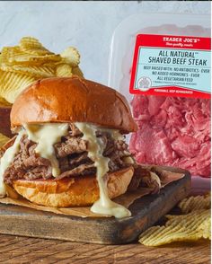 a pulled pork sandwich on a cutting board with chips