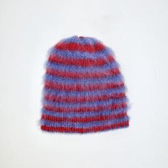 a red and blue knitted beanie sitting on top of a white surface