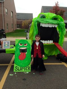 a young boy standing next to a green monster costume